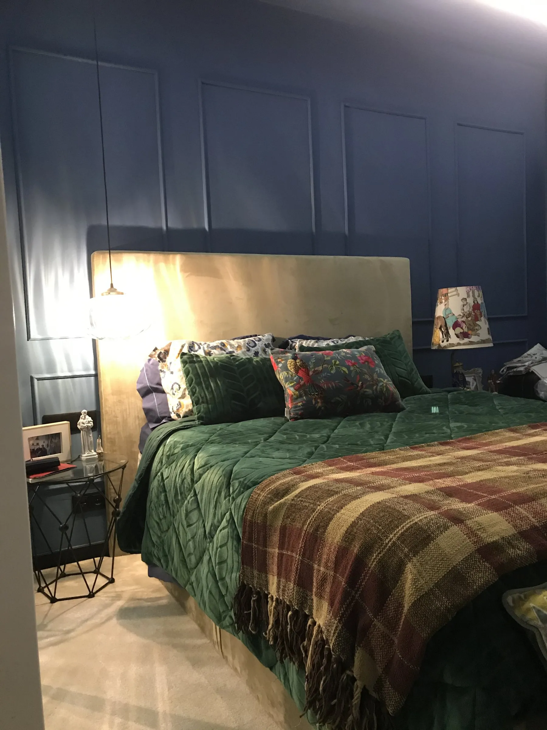 Quarto azul com molduras em boiserie, cabeceira estofada e colcha verde